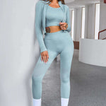 Powder blue workout set consisting of a cropped jacket, sports bra, and high-waisted leggings paired with white socks and sneakers