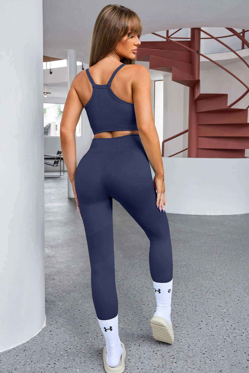 Navy blue workout set consisting of a sports bra and high-waisted leggings with white socks and sneakers